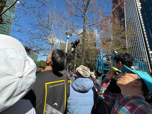 ▲信義廣場現場觀看大螢幕轉播的民眾，時不時轉頭確認大樓上的霍諾德。（圖／記者蕭涵云攝）