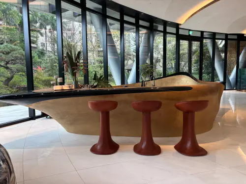 ▲將東方「筆墨紙硯」意境融入頂級豪宅！大廳這座極具藝術感的流線型吧檯，靈感正是取自「硯台」，深色檯面宛如墨池，展現中西合璧、獨特文化底蘊。（圖／記者徐銘穗攝）