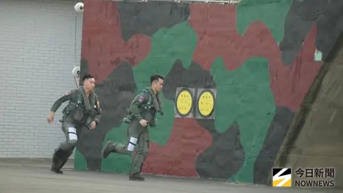 ▲115年國軍春節加強戰備媒體邀訪活動，空軍模擬警戒期間飛行員全副武裝穿戴抗G衣、求生背心及軀幹吊帶隨時待命，警鈴響起後，從警戒室以最快速度奔向F-16機庫出勤。（圖／記者呂炯昌攝）