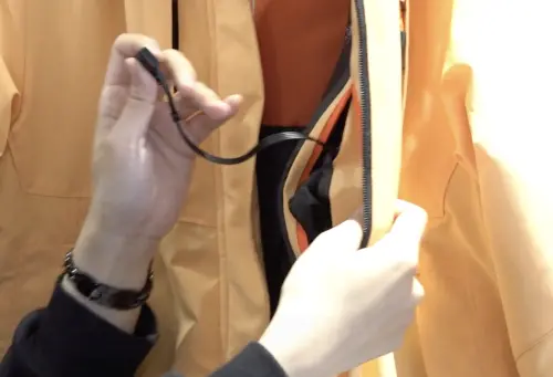 ▲門市店長提醒，智能升溫外套清洗前要把USB防水蓋蓋好，並收進口袋內拉起拉鍊就能直接丟洗衣機清洗。（圖／記者朱永強攝）