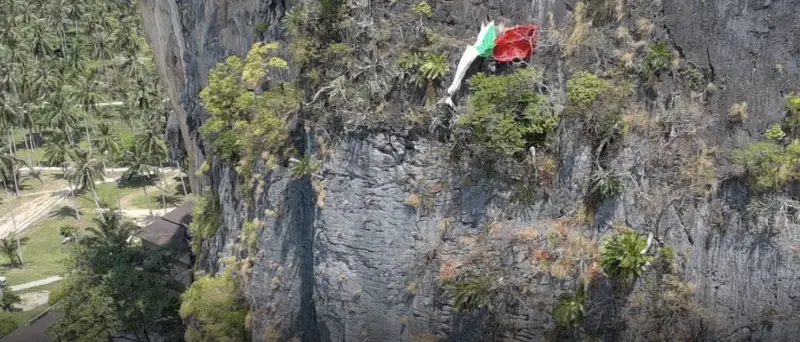 ▲英國男子在泰國喀比國家公園非法玩飛行傘，不慎撞上懸崖卡在半空中，救難人員花了6小時才成功救援。（圖／翻攝自The Thaiger）