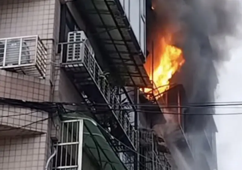 ▲信義區吳興街民宅1日清晨火警，陽台竄出火舌、濃煙密佈。消防出動29車96人搶救，救出1名40歲男住戶多處燒燙傷，另1名50歲女住戶無呼吸心跳送醫，起火原因仍待釐清。（圖／翻攝畫面）