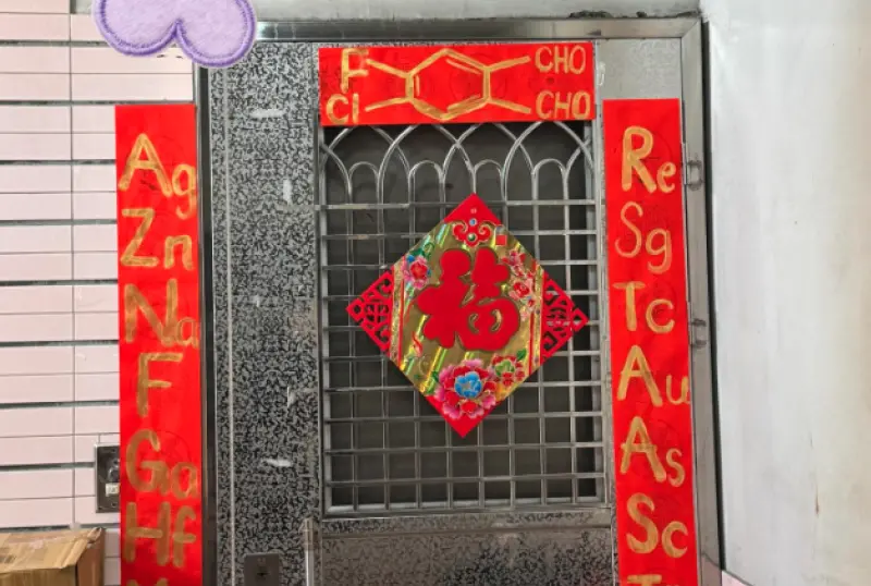 ▲有網友發現鄰居門口的春聯非常特別，整副春聯沒有半個中文字，完全不走傳統路線，而是整排英文字母與符號，仔細一看竟是化學元素，讓她困惑不已，求大神幫忙翻譯。（圖／翻攝自Threads@kin_niu_a）