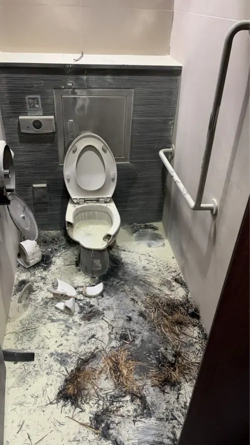 ▲善導寺捷運站男廁內遭縱火後一片慘狀，馬桶被燒毀、紙巾架掉落。（圖／翻攝畫面）