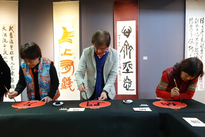 ▲華梵大學人文與藝術學院黃智陽院長（中）與其他書法家現場揮毫寫春聯。（圖／華梵大學提供）