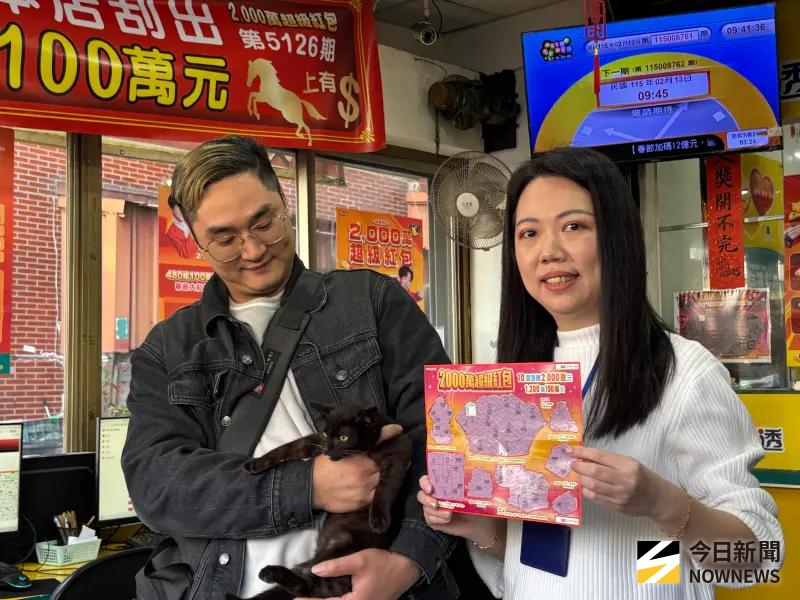 ▲刮中百萬陳姓男子今天抱著黑貓現身，彩券行店長石幸真展現刮中頭獎的刮刮樂。（圖／記者金武鳳攝，２０２６．２．１３）