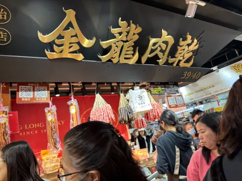 ▲擁有黑色底金色大字招牌的「金龍肉乾」格外顯眼，現場烘烤的碳燒金錢豬肉乾香氣四溢，是許多民眾指定的春節伴手禮。（圖／記者徐銘穗攝）