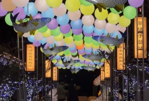 ▲桂花巷藝術村以「浪彩迎賓・年年有魚」為意象，取自鹿港潮間帶與藝術村作為烏魚寮前身的故事，彩球燈與魚群在空中遊走。（圖／鹿港鎮文化所）