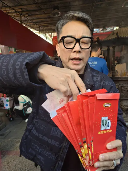 ▲迎接丙午赤馬年春節，命理大師詹惟中現身台北霞海城隍廟廣場發送108個紅包。（圖／民眾提供)