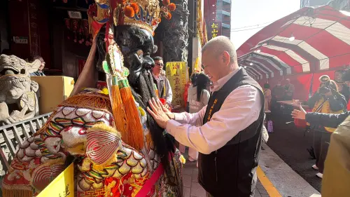 ▲松山霞海城隍廟委員陳瑋琪示範摸財神鬍鬚招財正確方式。（圖／記者黃韻文攝）