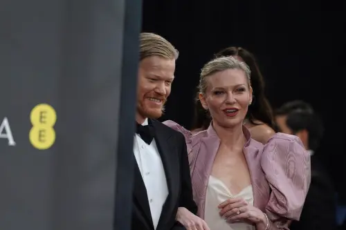 ▲克絲汀鄧斯特（右）和老公傑西普萊蒙一起出席，但她在白色低胸禮服外，還加上紅色外套，超大袖口的設計被稱為「像從1980年代的岳母找到靈感」，評價欠佳。（圖／美聯社／達志影像）　