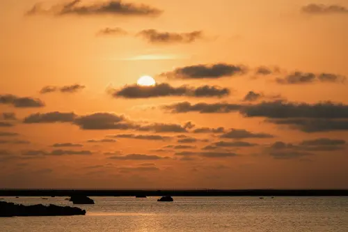 ▲夕陽落入宮古島佐和田之濱的海面，橘金色光暈映照海岸線之美。（圖／星宇提供）