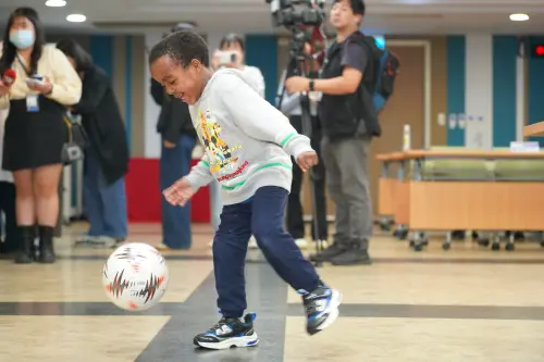 ▲Boum 母親 Rose 上台分享跨海求醫 180 天心路歷程；期間 Boum 一直在會場蹦蹦跳跳、踢著北醫附醫送的足球，滿溢著重拾行動自由的喜悅。（圖／北醫附醫提供）