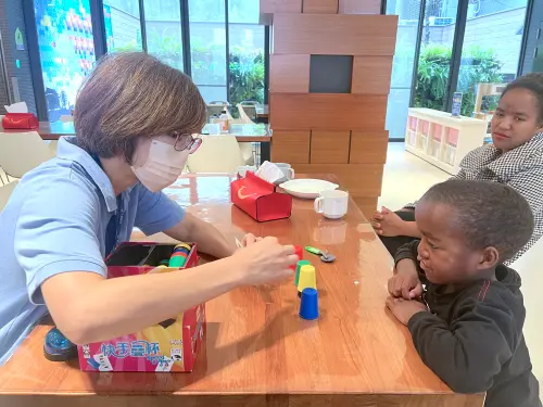 ▲語言不同仍能交流，志工與孩子透過桌遊互動陪伴等待手術的時光。（圖／麥當勞叔叔之家提供）