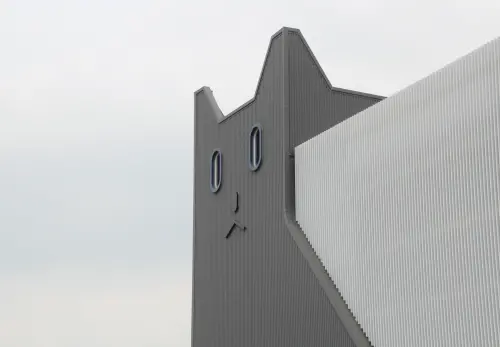 ▲建築是由一隻趴在地上的白色巨貓作為造型，建築側邊也有數隻瞪大眼睛的黑貓，讓人一眼就能看出是生產貓食的工廠。（圖／記者鍾泓良攝影）
