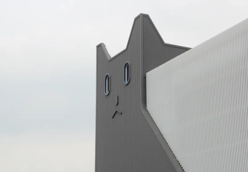 ▲建築是由一隻趴在地上的白色巨貓作為造型,建築側邊也有數隻瞪大眼睛的黑貓,讓人一眼就能看出是生產貓食的工廠。(圖/記者鍾泓良攝影)