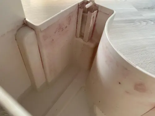 ▲這角落你看過嗎？ 實拍除濕機塑料水箱內壁與角落，出現大面積陳年的粉紅色水垢與黏液（圖）。新光醫院家醫科醫師柳朋馳指出，這層粉紅物質即為致病的「黏質沙雷氏菌」生物膜，代表水箱已成細菌堡壘。（圖／記者徐銘穗攝）