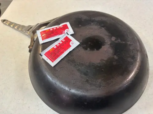 ▲記者準備家中焦黑嚴重的平底鐵鍋、過期番茄醬及保鮮膜，實測網路清潔妙招。（圖／記者徐銘穗攝）