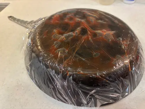 ▲將番茄醬厚敷並以保鮮膜緊密包覆，目的是讓酸性成分長時間「巴住」焦垢。（圖／記者徐銘穗攝）