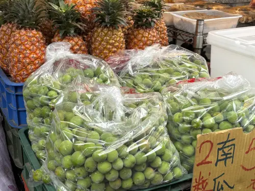 ▲傳統市場水果攤上擺滿當季青梅，受氣候影響今年果實普遍偏小。雖產地加工收購價跌至每公斤 15 元慘賠，但批發市場均價仍維持在 59.9 元。內行正趁便宜搶購，準備用「黃金比例」DIY 梅酒。（圖／記者徐銘穗攝）