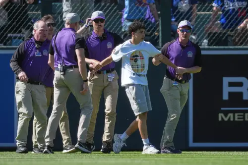 ▲一名球迷突然從觀眾席翻越護欄衝入球場，並全速朝左外野方向奔跑，遭保全擒獲。（圖／美聯社／達志影像）