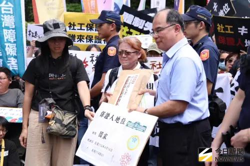 ▲社工團體總計超過千人前往行政院抗議，由內政衛福勞動處副處長賈裕昌（圖右）接下陳情書。（圖／記者朱永強攝）