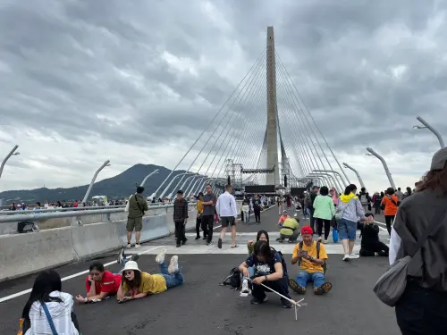 ▲機會真的難得！淡江大橋通車前開放健行，有民眾直接在橋面上「躺平」拍照，感受壯闊橋體與河口海風，把握這輩子可能唯一一次能趴在路中央打卡的奇特體驗。（圖／記者徐銘穗攝,2026.04.25）