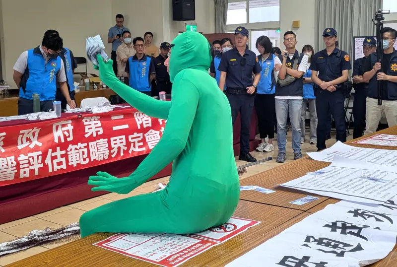 ▲「戰鬥茶師」常行深今天改穿綠色緊身衣，在名間焚化爐環評會議大灑千元鈔。（圖／中部環團提供，2026.04.27）