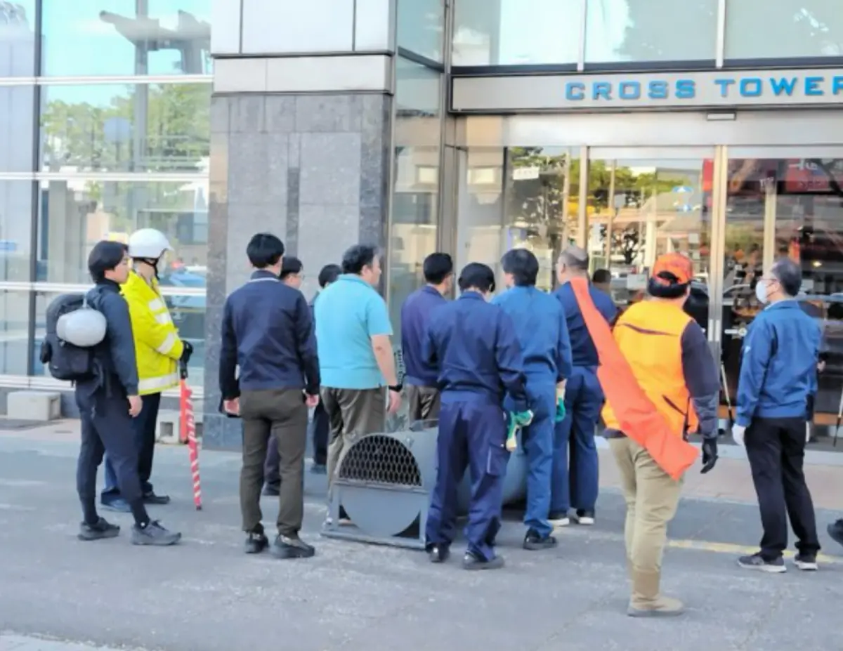 ▲日本青森縣15日下午發生黑熊闖入鬧區大樓的驚悚事故。圖為在場人士設置陷阱試圖誘捕。（圖／翻攝自朝日新聞）