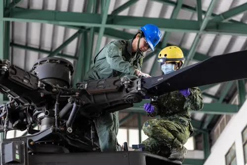 Two ROC Army personnel inspect and prepare an armed helicopter for a training flight. (MNA)