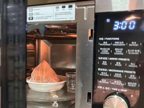 ▲記者實測微波肉粽關鍵2動作：用濕廚房紙巾將肉粽完全包覆，並在旁邊放半杯水維持濕潤。（圖／記者徐銘穗攝）