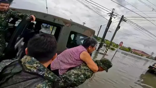 ▲官兵在深及腰際的積水中背負行動不便長者至安全場所。（圖／記者莊全成翻攝）