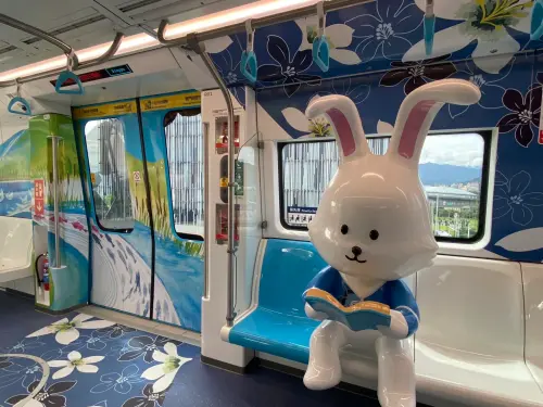 ▲客家文化主題車廂內佈滿幾何藍染與桐花圖騰，博愛座旁更有超吸睛的讀書白兔公仔，展現當代客家新美學。（圖／新北捷運局提供）