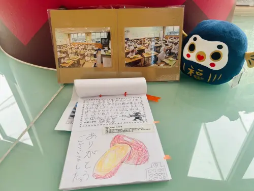 ▲ 防府市小朋友們回贈的相片及與畫冊展示在永華市政中心6F國際廊道，有的小朋友貼心附上中文翻譯表達感謝。（圖／南市府提供）