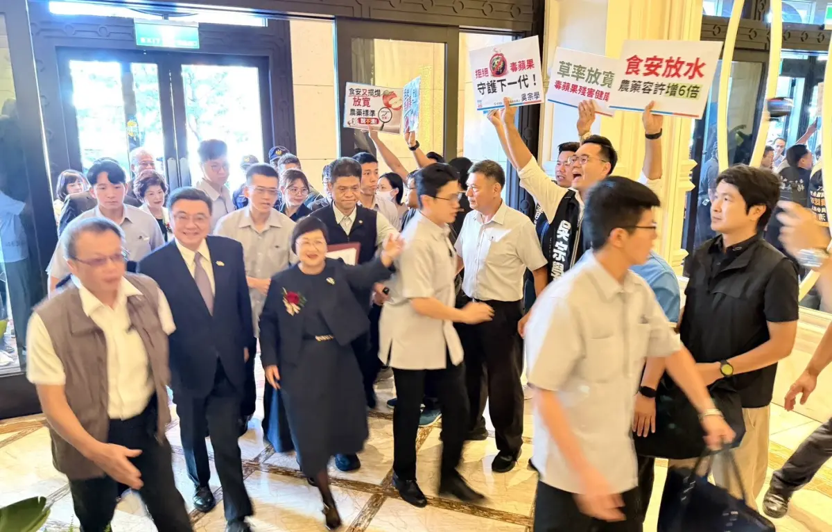 ▲台中市議員楊大鋐等人在行政院長卓榮泰入場時，高舉標語抗議。（圖／吳宗學提供，2026.07.15）