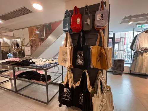 ▲實際走訪 NET 南京二店二樓，樓梯口展示架掛滿各式「台灣」與「珍珠奶茶」圖案的托特包。（圖／記者徐銘穗攝）