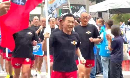 ▲江啟臣穿著紅短褲，在海龍蛙兵同的陪同下，拿著大型國旗跑進登記會場。（圖／記者顏幸如攝，2026.09.03）