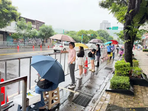 ▲下午4時許基河路街道兩旁有零星民眾撐傘等候。（圖／記者周淑萍攝）