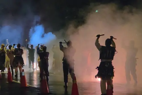 ▲表演者在煙霧與火光中敲擊樂器前進，雨夜街頭瞬間充滿強烈戲劇張力。（圖／記者周淑萍攝）