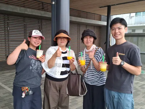 ▲熊本近日仍處高溫，許多災區的民眾在喝下冰涼美味的果汁後，也展露出開心笑容。（圖／南市府提供）