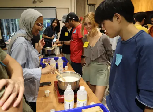 Kayra looks at the camera as youths from home and abroad make tofu. (TDDA)
