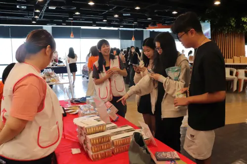 ▲中秋公益市集現場提供手工餅乾等義賣品，志工向蝦皮購物員工介紹商品內容，鼓勵線上線下雙軌支持義賣。（圖／品牌提供）