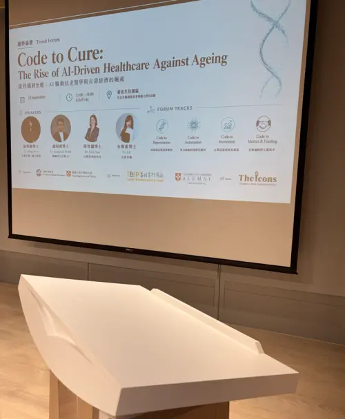 Photos of the speakers are presented on a slide in front of the podium. (TCN)