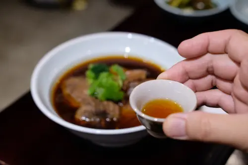 ▲「川生渝味」的牛肉麵還會附上一小盅女兒紅，麵吃到中段時可再加入湯頭內，帶出更圓潤飽和的升級感受。（圖／記者葉盛耀攝）