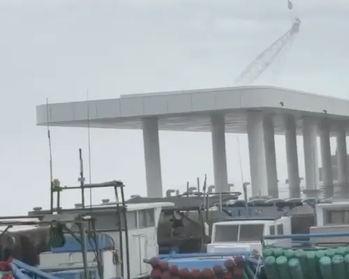 ▲中颱薔琵狂風掀起巨浪，台東富岡漁港岸邊一輛重型吊車慘遭擊落墜海。（圖／Threads網友「open_1225mr 」授權使用）