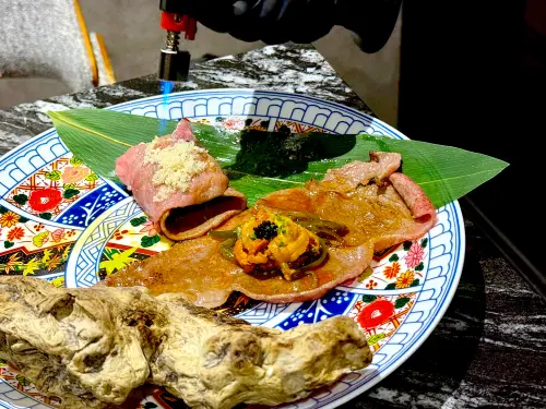 ▲專人桌邊手工捲製「剝皮辣椒F1和牛雲丹卷」。（圖／記者蕭涵云攝）
